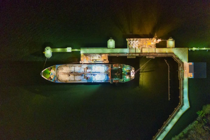 Aerial top-down view of a tanker docked at a terminal during industrial maritime operations.